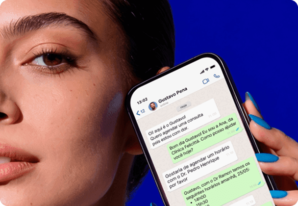 Mulher segurando o celular com uma conversa no WhatsApp em que a Secretária IA do Simples Dental agenda uma consulta com o paciente